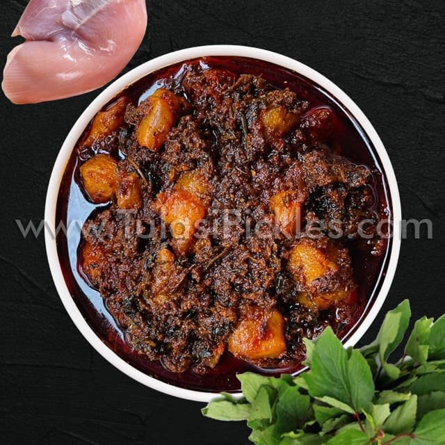Bowl of hearty beef and potato stew in a dark sauce, with fresh herbs nearby on a black surface.