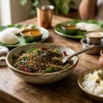 Rustic table setting with Indian meal: bowl of spiced lentil mix with greens and seeds, beside a bowl of white rice topped with seeds.